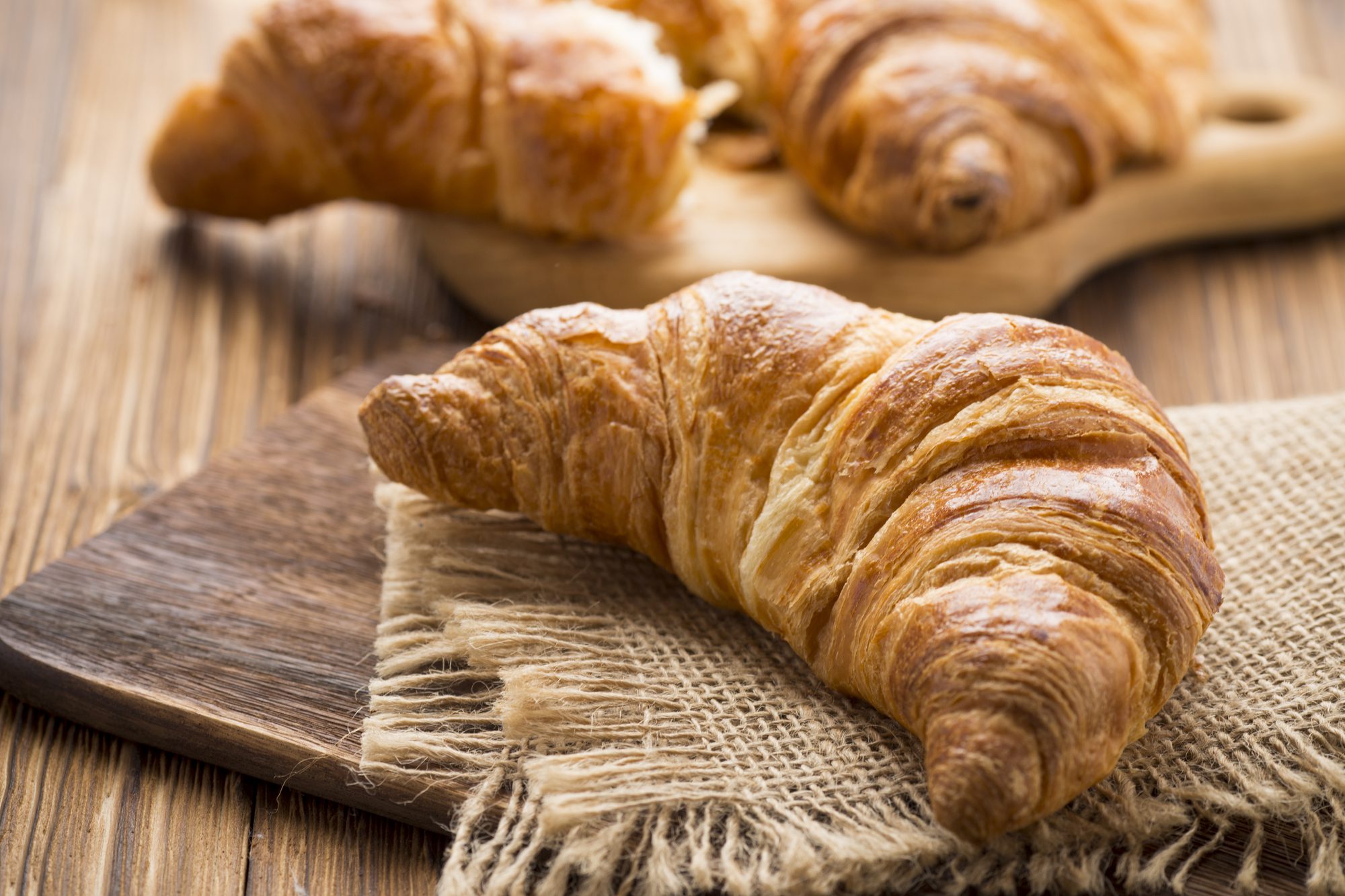Delicious, golden croissants resting on a wooden table